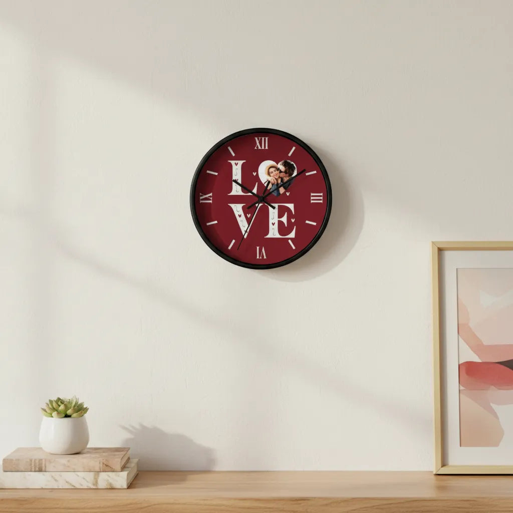 Wall clock with 'LOVE' design on a wall with a plant and framed picture below.