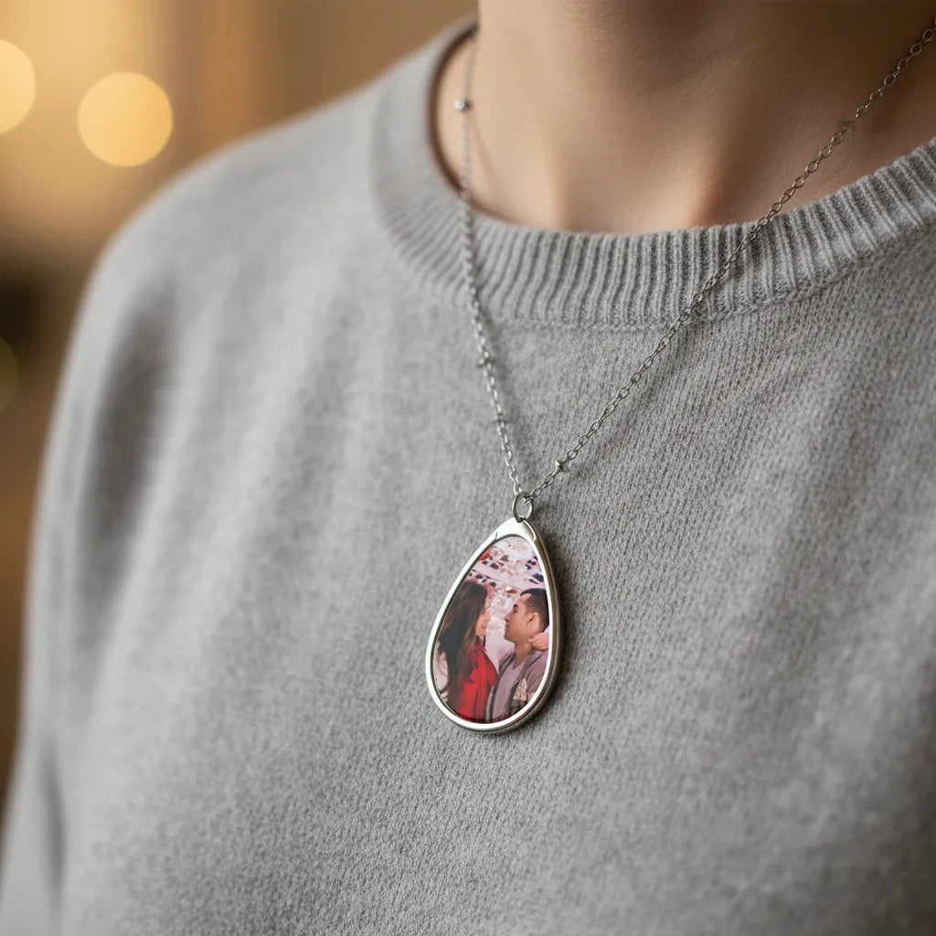 Teardrop-shaped pendant with a photo on a gray sweater against a blurred background