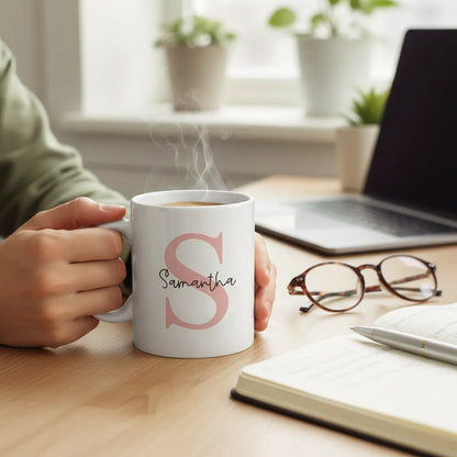Person holding a mug with 'Samantha' on it, sitting at a desk with a laptop and glasses.